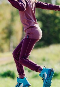 Sporty outfit med en bordeaux langærmet top og matchende bukser. Blå vandrestøvler med tydeligt mønster. Komfortabelt, fleksibelt materiale.