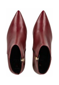 Botas de tobillo de cuero burdeos con punta afilada, cremalleras laterales, textura suave y detalles de hardware mínimos.