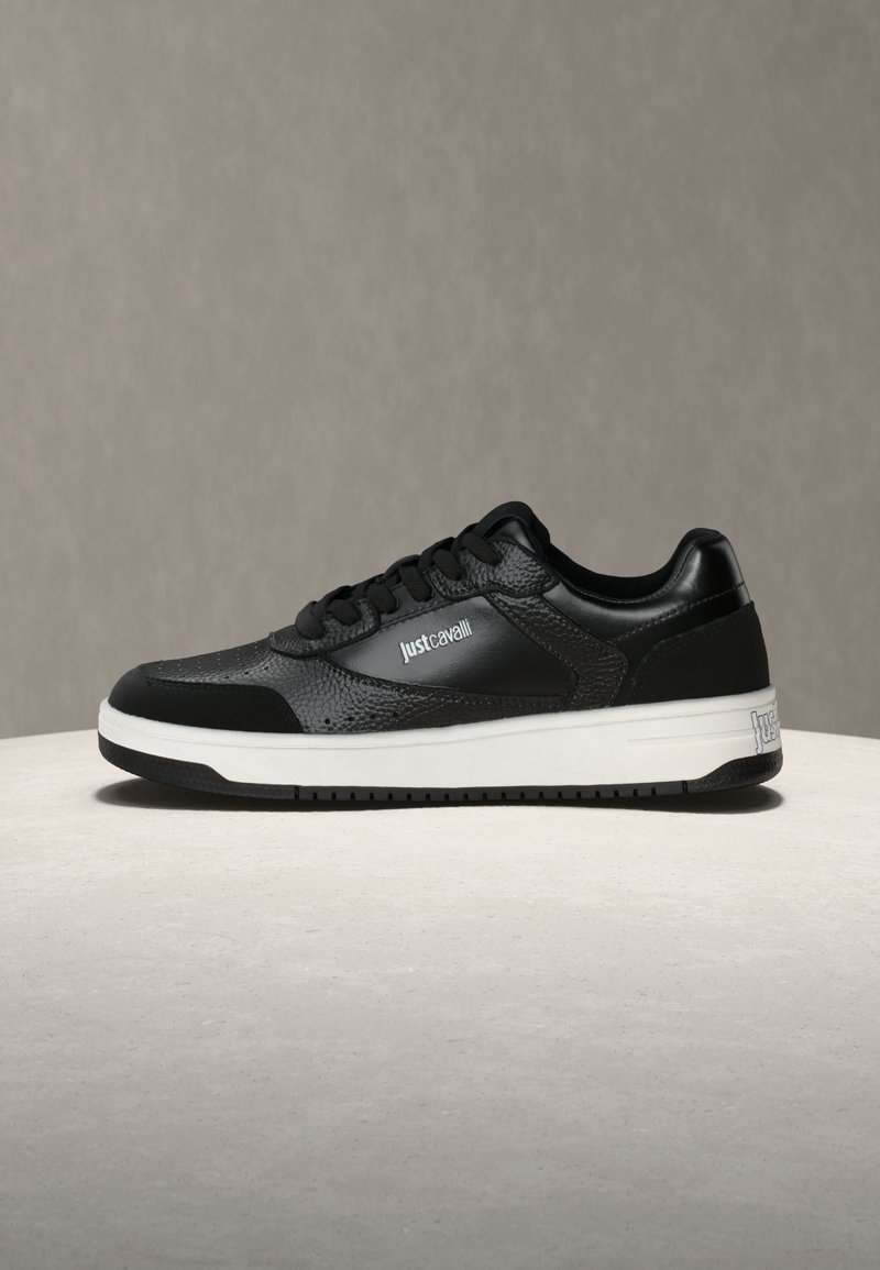 Črni usnjeni nizki supergi z belo podplatom, z blagovno znamko "Just Cavalli" na strani in peti, prikazani na svetli površini z nevtralnim ozadjem.
