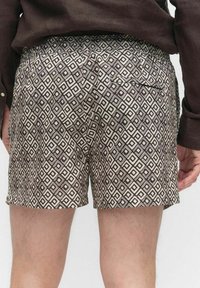 Gedrukte shorts van lichtgewicht stof, met een bruine en crèmekleurige geometrische ruitpatroon. Inclusief een achterzak en elastische tailleband.