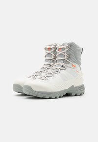 Botas de senderismo blancas y grises con una parte superior текстurada, punteras reforzadas y acentos naranjas; con un diseño de cordones y suelas resistentes.