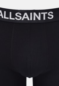 Svarta bomullshorts med bred resårmidja som har "ALLSAINTS" i fet vit text. Slät textur, åtsittande design och inga ytterligare mönster.