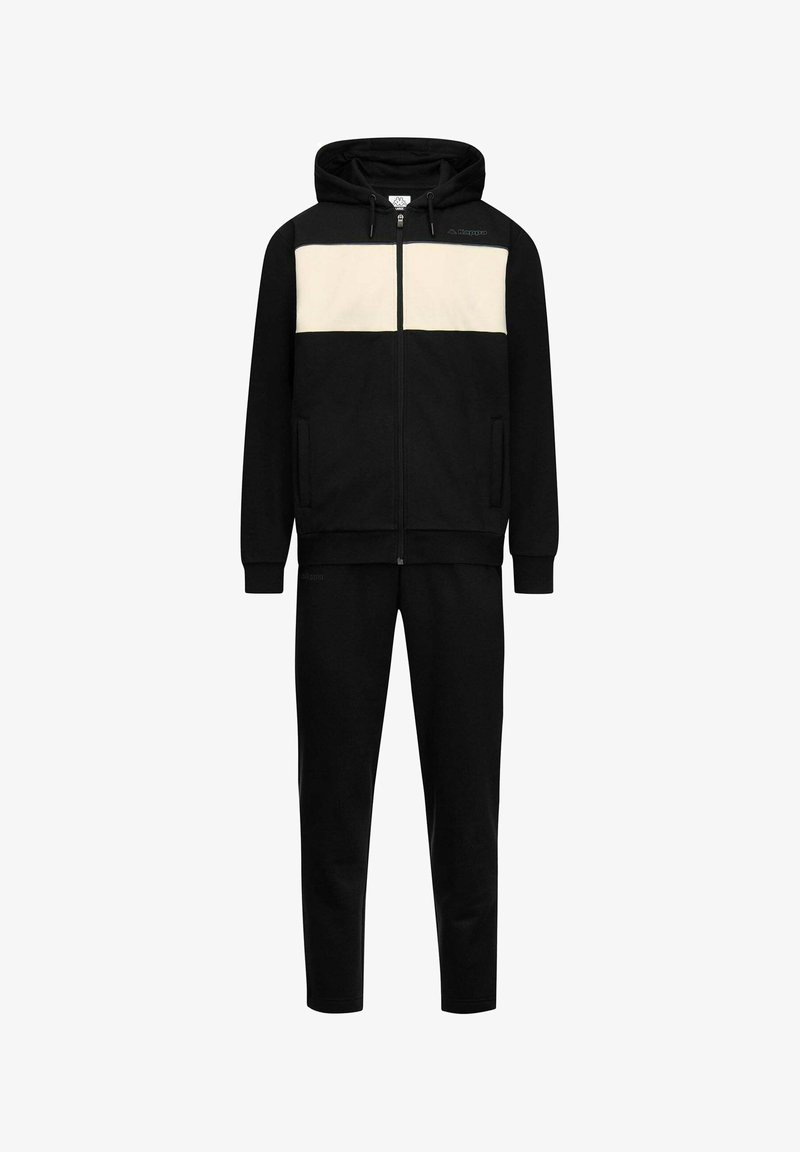 Tuta nera con striscia orizzontale color crema sul petto, felpa con cappuccio e zip con coulisse, e pantaloni coordinati.