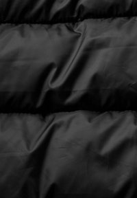 Tissu noir matelassé avec des coutures horizontales et une texture lisse, légèrement froissée.