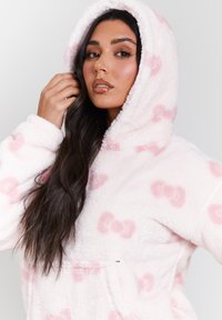 Huvtröja i mjuk rosa med ljusare rosa bågmönster, med en kenguruficka och ribbade ärmslut, som ger värme och komfort.