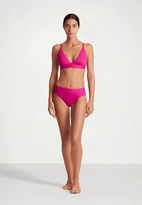 Magentos spalvos bikini komplektas, kuriame yra trikampio formos braletė su plonomis petnešėlėmis ir derančios žemo liemens kelnaitės, pagamintas iš lygaus, tampraus audinio.