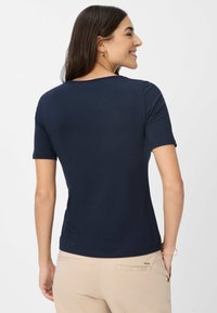 Marineblå kortærmet T-shirt lavet af blød stof, med en rund halsudskæring og en afslappet pasform. Synlig syning detaljer ved kanten.