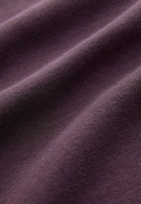 Lilla bomuldsstof med en glat tekstur og subtil ribbet mønster, der viser bløde draperinger og milde folder.