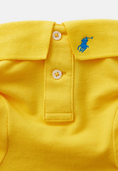 Polo giallo realizzato in tessuto testurizzato, con patta di chiusura a bottoni bianchi e un logo ricamato blu sul colletto.