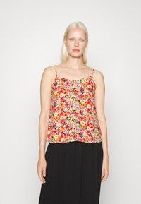 Camisola floral com padrões multicoloridos num tecido leve, com alças finas e um corte descontraído, combinada com uma saia preta.
