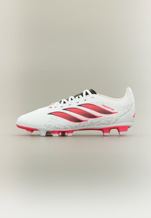 Białe i różowe korki piłkarskie Adidas Predator z czarnymi sznurówkami i czerwonym logo z trzema paskami, pokazane z profilu na neutralnym tle.