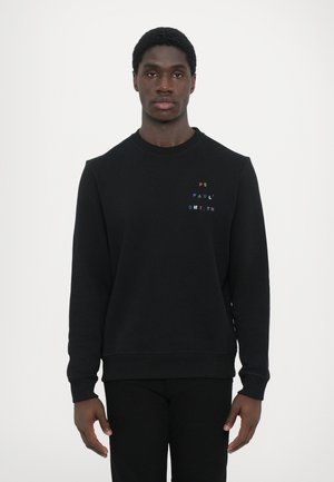 Svart hettegenser med ribbede mansjetter og krage, med flerfarget broderi som skriver "PS PAUL SMITH" på brystet. Vanlig passform.