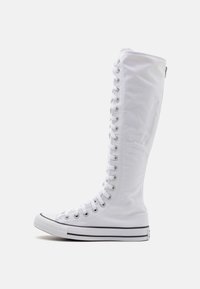 Sneakers bianchi alti in tela con una finitura testurizzata, sistema di allacciatura lungo e punta in gomma; presentano una striscia nera lungo la suola.