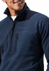 Navyblauer Fleece-Pullover mit hohem Kragen, halbem Reißverschluss, strukturiertem Stoff und kleinem Logo. Verfügt über eine durchgehende Brusttasche mit Reißverschluss und dezente Nähte.