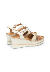 Sandalias de cuña con un diseño de punta abierta, que cuentan con acentos en tono marrón y metálico, correas de cuero blanco y una suela texturizada y trenzada.