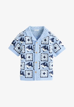 Lichtblauwe korte mouwen gehaakte cardigan met knopen voorop en afwisselende walvis- en geometrische vierkante patronen in marineblauw en wit.