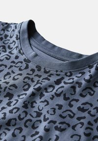 Primo piano di una maglietta blu a girocollo con un motivo di stampa leopardata nera sulla stoffa.