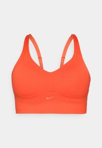 Sujetador deportivo de Nike en un brillante color naranja, con una textura suave, tirantes ajustables y un pequeño logo blanco en el centro delante.