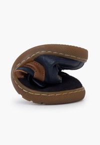 Brown and navy shoe with a flexible design, featuring a textured rubber sole and a velcro strap. Soft fabric lining is visible inside.