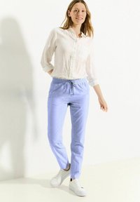 Světle modré kalhoty na šňůrku vyroben�é z lnu, v kombinaci s bílou košilí na knoflíky a bílými teniskami. Hladká textura a pohodlný střih.