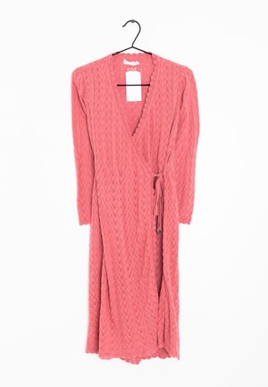 Robe portefeuille en maille à manches longues rose avec bords festonnés et ceinture nouée, suspendue sur un cintre noir avec une étiquette de prix blanche.