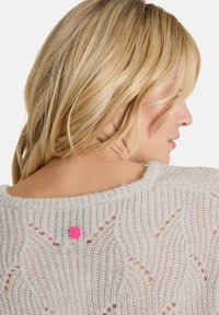 Hellgrauer Strickpullover mit strukturiertem, offenem Gewebe, runder Ausschnitt und einem pinken Knopfdetail am Rücken.