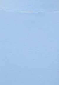 Tissu bleu clair avec une texture lisse, présentant un ourlet droit et des coutures discrètes sur le bord supérieur, uniformes dans l'ensemble.