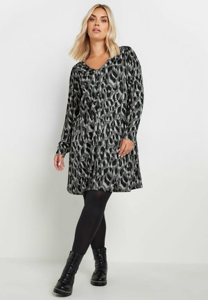 Zwarte en grijze luipaardprint jurk met lange mouwen en een V-hals, voorzien van knoopdetails en een losse pasvorm voor comfort. Te combineren met zwarte leggings en laarzen.
