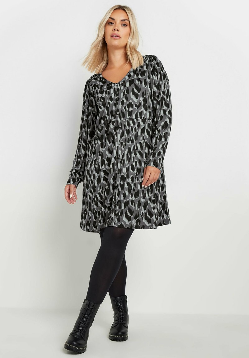 Sukienka w czarno-szare cętki z długimi rękawami i dekoltem w kształcie V, z detalami w postaci guzików i luźnym krojem dla wygody. Idealna do zestawienia z czarnymi rajstopami i botkami.