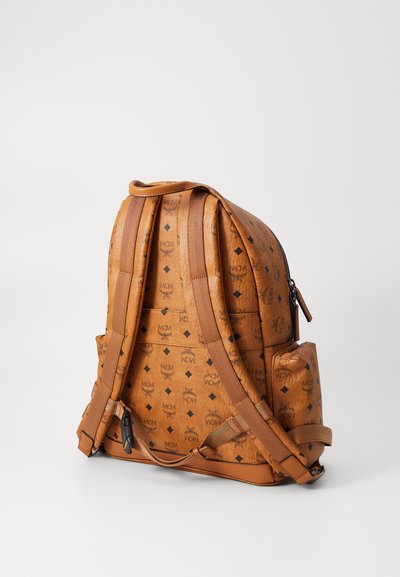 Zaino in finta pelle marrone con stampa logo nera, spallacci regolabili e tasca con cerniera. Presenta un design trapuntato e una tasca laterale.