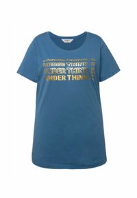 Camiseta de algodón azul con cuello redondo y mangas cortas. Presenta un texto en metalizado dorado, en un patrón repetido, que dice "UNDER THINK IT".