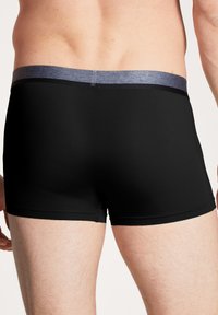 Zwarte boxershorts met een grijze tailleband. De stof lijkt glad met een strakke pasvorm, afgestemd op een lengte tot halverwege de bovenbenen. Geen zichtbare patronen.