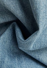 Lichtblau denimstof met een gladde textuur en subtiele weefpatronen, die zowel diepte als zachtheid in het materiaal tonen.