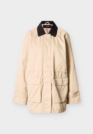 Veste beige avec col en velours côtelé noir, poches à rabat à l'avant, manches longues avec sangles ajustables et fermeture boutonnée dissimulée.