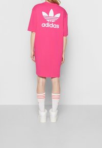 Rosa oversized t-shirt klänning med vit logotyp på baksidan, tillsammans med vita strumpor med rosa ränder. Mjuk tyg och avslappnad passform.