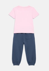 Back view of toddler outfit with light pink short-sleeve shirt and navy blue elastic cuff pants with back pocket.