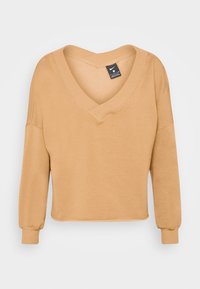 Sudadera de manga larga con escote en V en color beige claro. Material suave con puños acanalados. Diseño corto con un sutil detalle de costura en el escote.