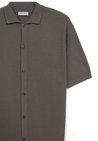 Kurzarm-Poloshirt in einem gedämpften Olivton, mit einem strukturierten Waffelmuster und schwarzen Knöpfen entlang der Vorderseite.