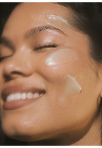 Fuktighetskrem påført kinn og panne, glatt, gjennomsiktig, geléaktig tekstur; nærbilde av hud med myk glans og naturlig tone.