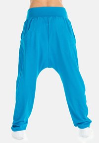 Turquoise harem broek met een brede elastische tailleband, voorzien van zijzakken en een losse, taps toelopende fit bij de enkels. Soepele stoftextuur.