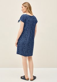 Tummansininen mekko lehtikuviolla, lyhyet hihat nauhoilla ja rento leikkaus. Materiaali vaikuttaa kevyeltä, sopii arkikäyttöön.