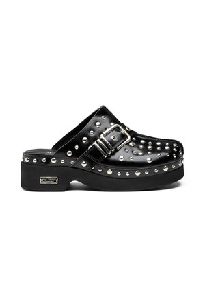 Scarpa slip-on in pelle nera con borchie argentate, una grande fibbia argentata e una suola platform spessa.