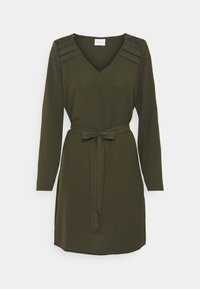 Olivgrön klänning med långa ärmar, V-ringning och ett matchande bälte i samma tyg i midjan. Har texturerade axelaccenter.