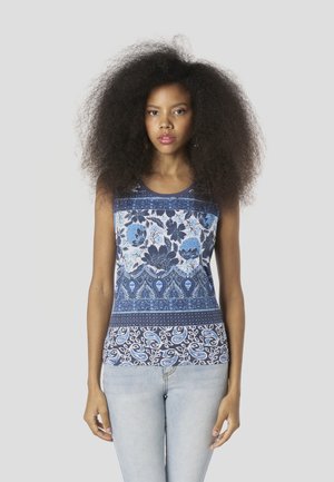 Top azul sin mangas con estampados florales y de cachemira, con diseño de capas y escote redondo, combinado con mezclilla clara.