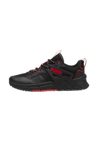 Zapatilla deportiva negra con acentos rojos, que cuenta con una parte superior texturizada, un cuello acolchado y un diseño de mediasuela angular destacado. Cierre con cordones.