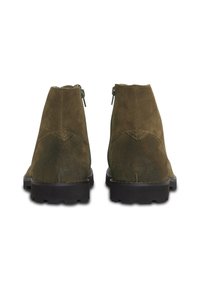 Botines de ante verde con una cremallera abierta en la parte trasera, que presentan una suela de goma negra sólida y un diseño de costura.