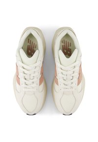 Sneakers med en krämfärgad nätövre, ljus persikofärgade mockadetaljer, vita snören och en texturerad gummisula. Följande logotyp inuti skon.