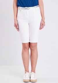 Bermuda short in denim bianco con risvoltini, caratterizzati da una vestibilità slim. Abbinati a un top blu e sneakers bianche con lacci. Include una cintura argentata.