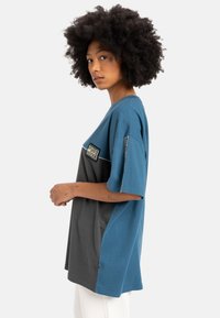 Korte mouw t-shirt met een blauw en grijs kleurblokdesign, van katoen, ronde halslijn en een decoratieve patch op de borst.