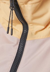 Lättviktig jacka med en gul huva och en svart dragkedja. Tyget är slätt med en subtil lyster, i en blandning av lavendelfärg och krämfärg.